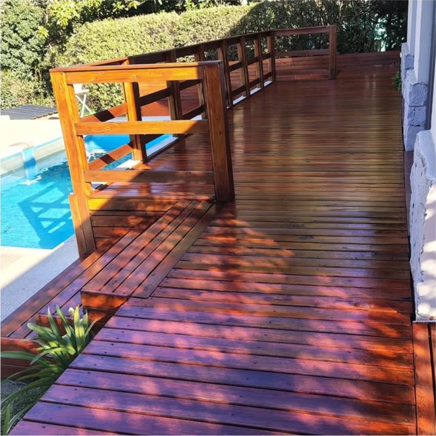 Deck de madera barnizado junto a una pileta con baranda